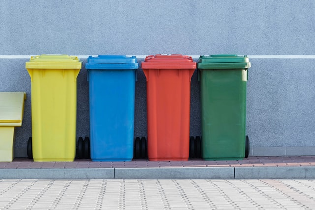 yellow, blue, red and green trash bins lined up outside
